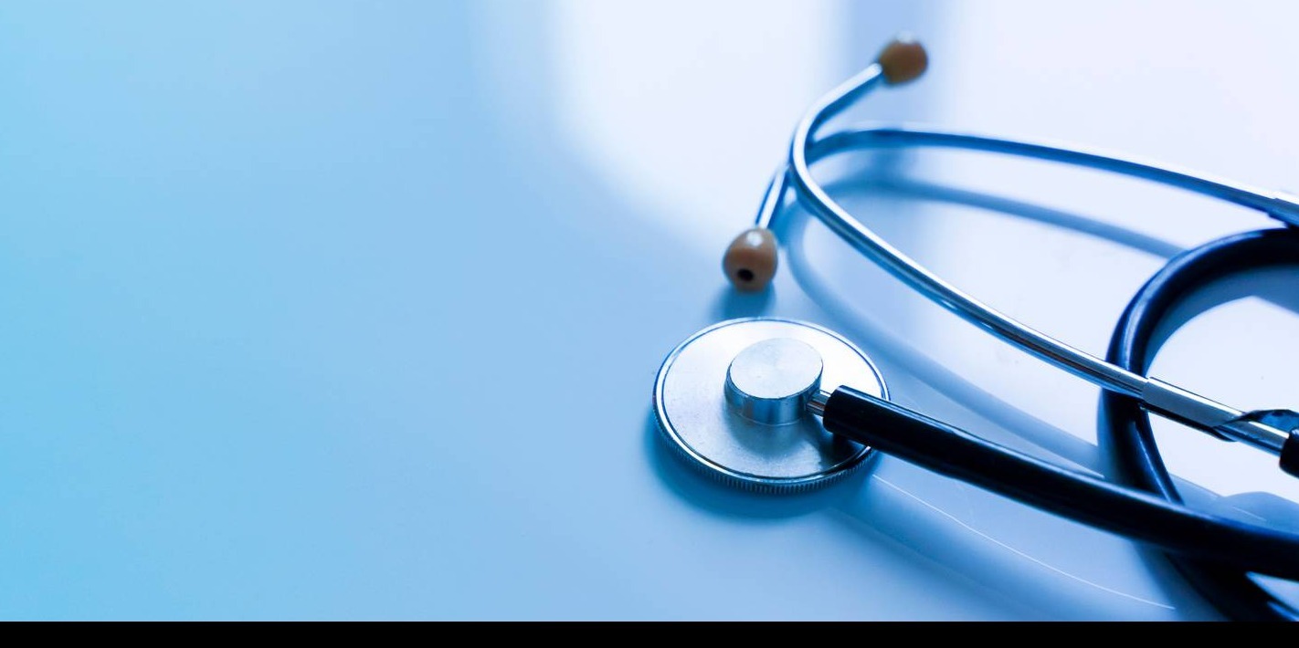 A stethoscope lying on a light blue surface.